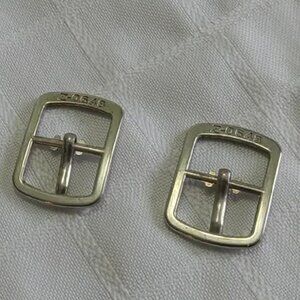B- Two vintage silver-colored watch buckles